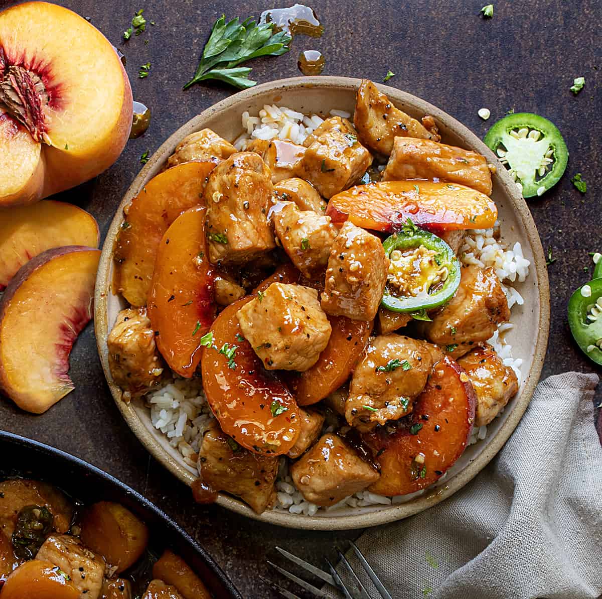 Plate of Jalapeno Peach Pork Bites on a Bed of Rice Next to Fresh Peaches from Overhead.