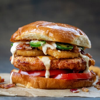 A Rodeo Crispy Chicken Sandwich on a Dark Table with Onion Rings.
