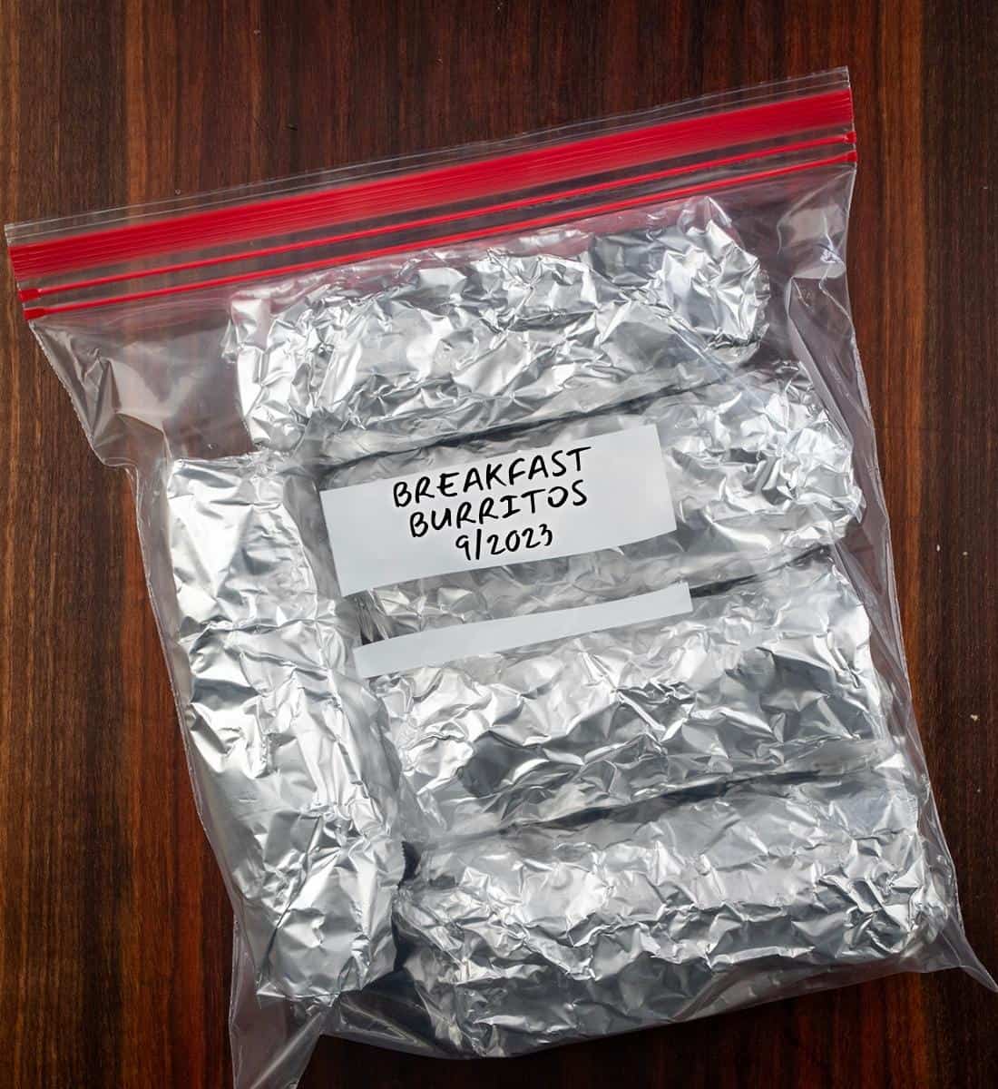 Plastic Bag Filled with Burritos Wrapped in Foil and Labeled for Freezing.