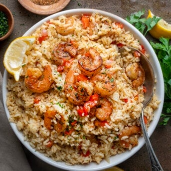 Bowl of Cajun Shrimp and Rice on a Table with a Spoon in the Bowl.