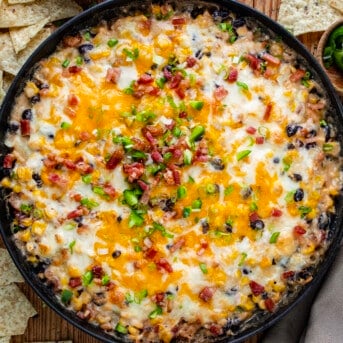 Skillet of Bakied Cheesy Baked Cowboy Dip with Chips Around it From Overhead.