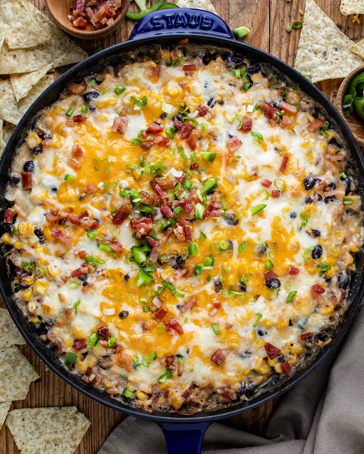 Skillet of Bakied Cheesy Baked Cowboy Dip with Chips Around it From Overhead. 