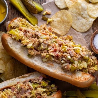 Cuban Chopped Grinder Sandwiches on a Table with Pickles, Chips, More Sandwiches.