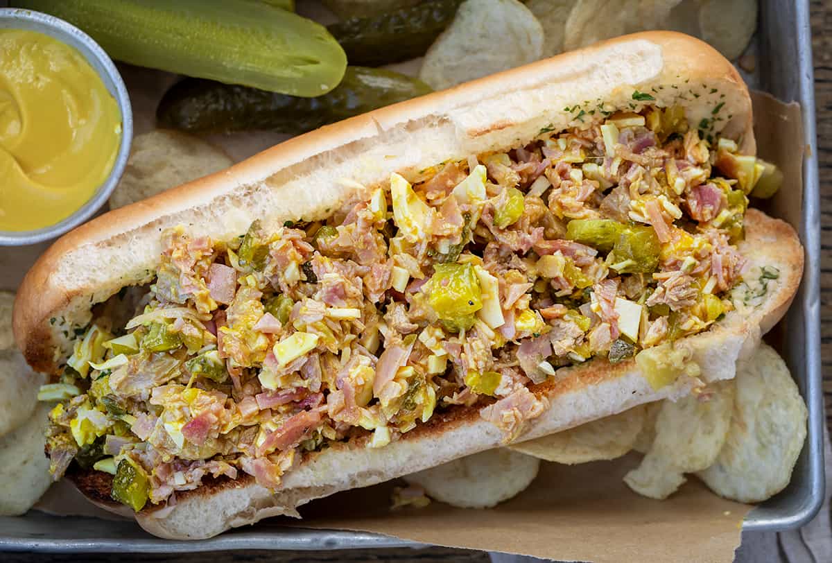 One Cuban Chopped Grinder Sandwich in a Basket with Chips and Pickles.