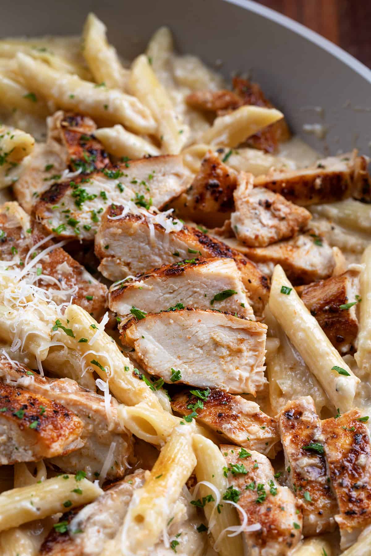 Close up of sliced chicken on creamy french onion pasta.