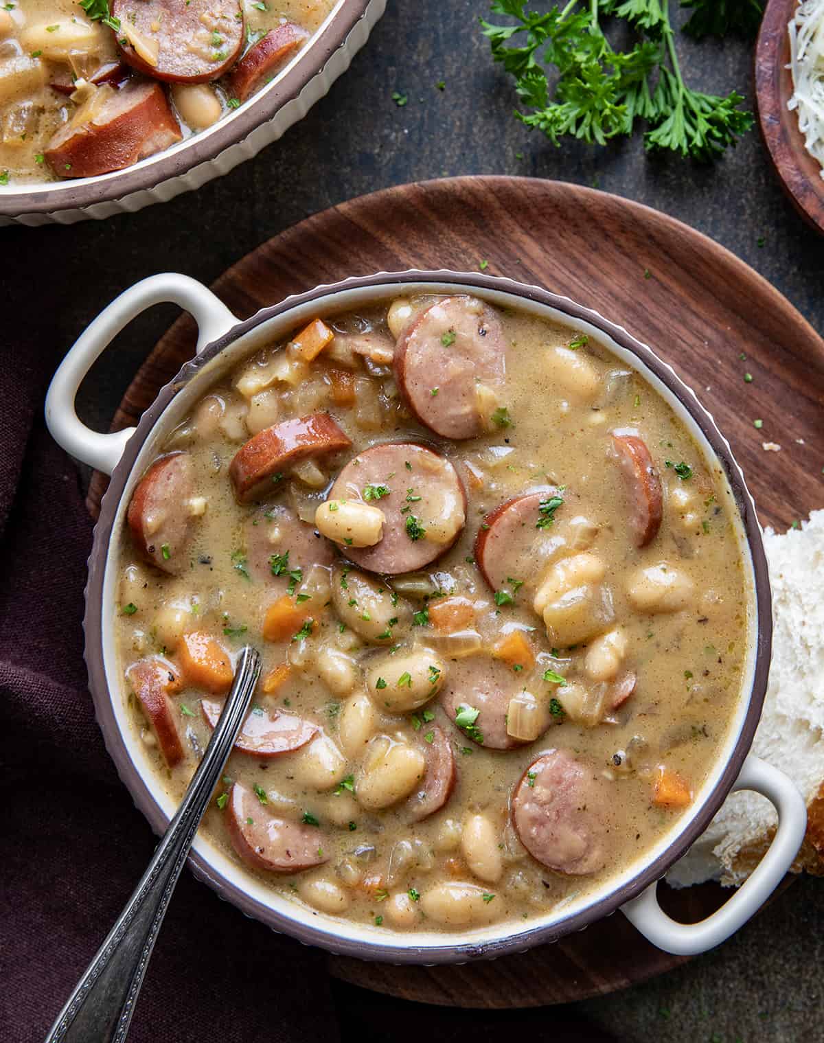 Bowls of Creamy Bean Soup With Kielbasa on a Dark Table with Spoon.