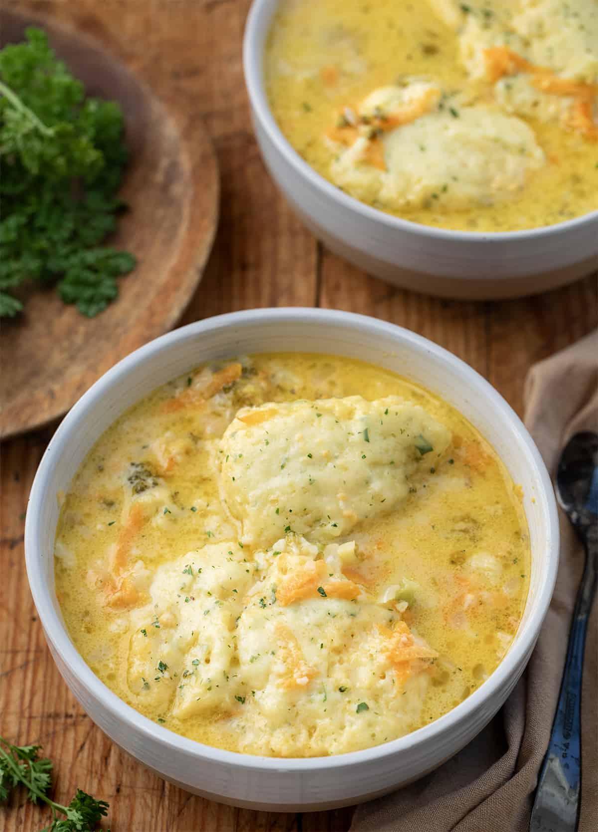 Bowls of Broccoli Cheese Soup With Dumplings on a Wooden Table.
