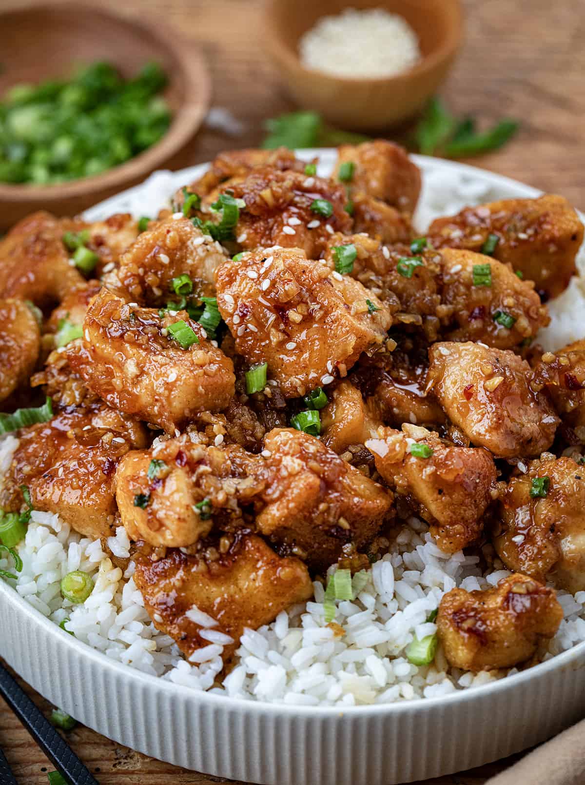 Plate of Honey Garlic Chicken Bites on a bed of rice on a wooden table.