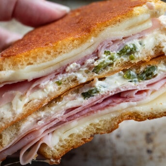 Hand holding a cut in half Jalapeno Ham Grilled Cheese showing inside layers.