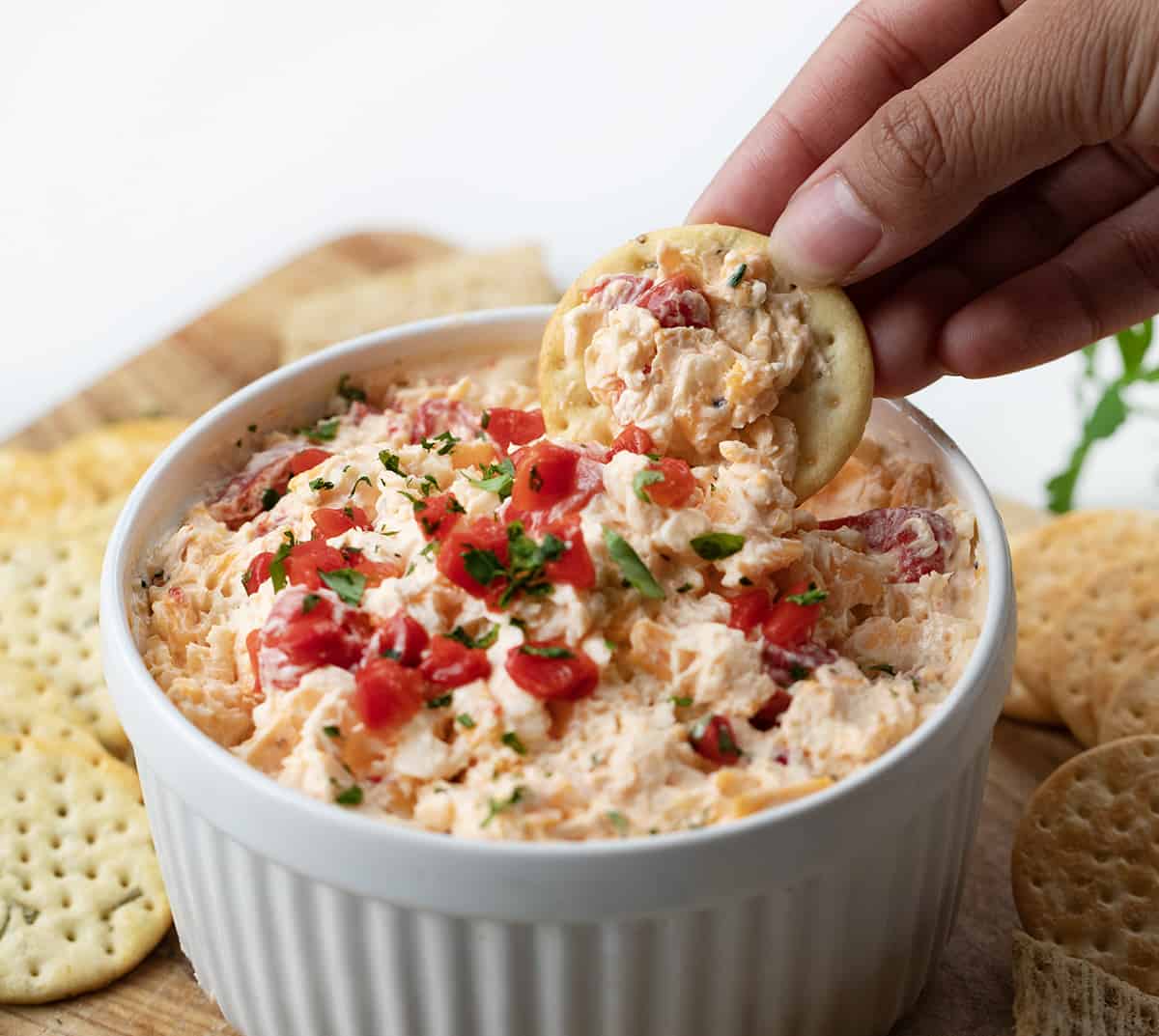Hand scooping up Pimento Cheese with a cracker.