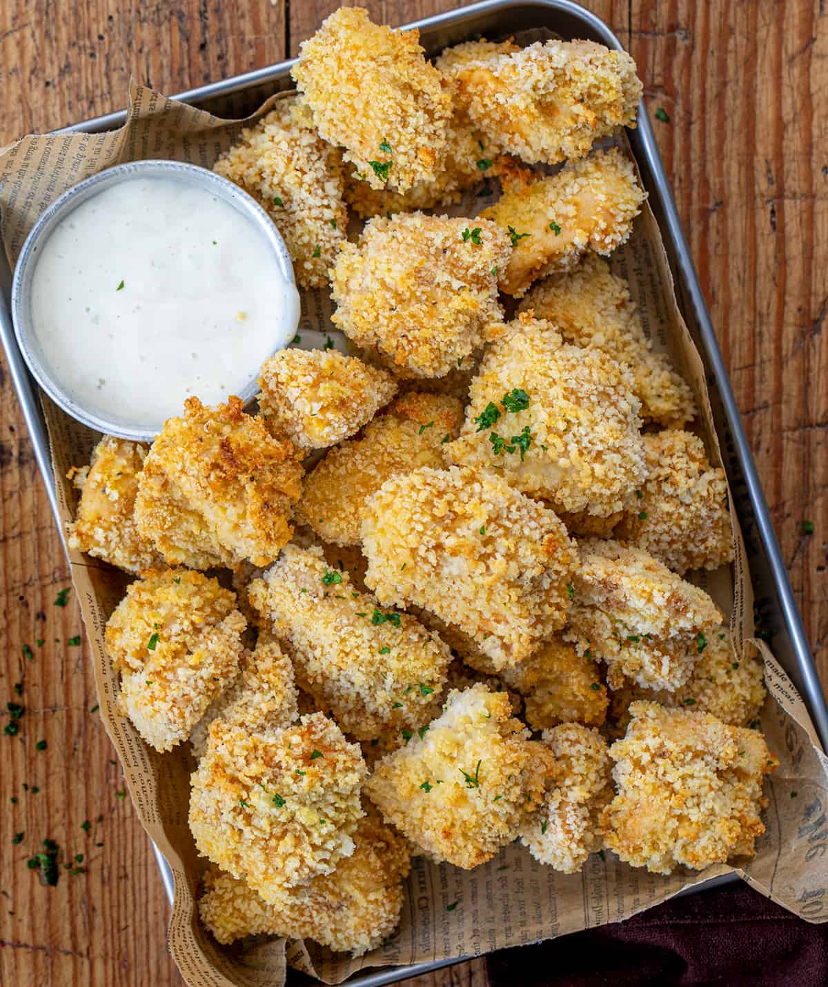 Pan of Baked Popcorn Chicken on a Wooden Table. 