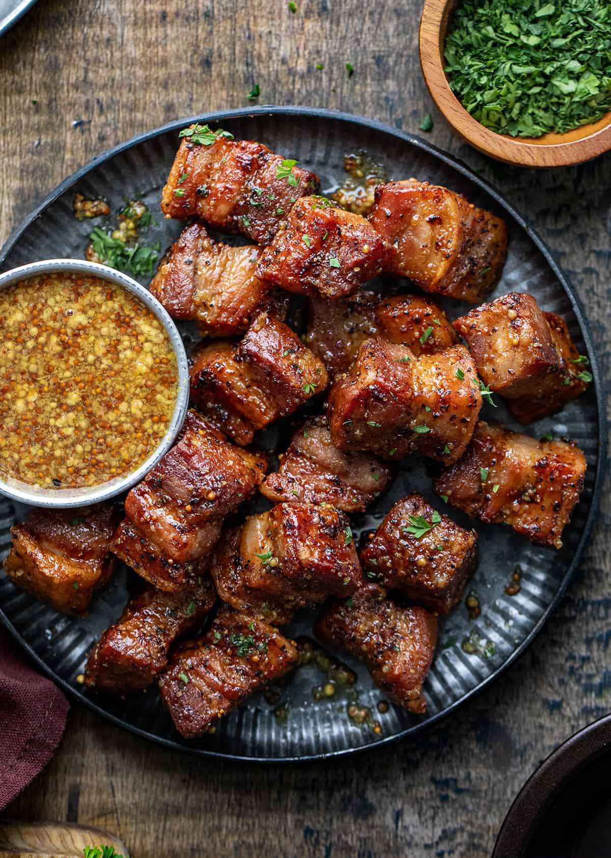 Plate of Maple Mustard Pork Belly Bites on a Dark Counter with Mustard Sauce. 