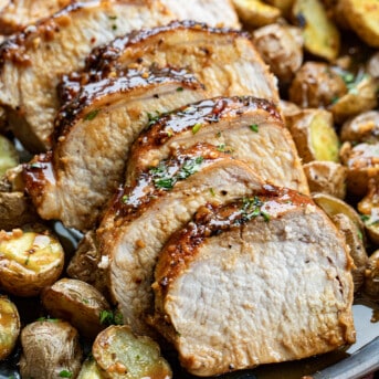 Honey Garlic Pork Loin cut into slices and surrounded by potatoes.