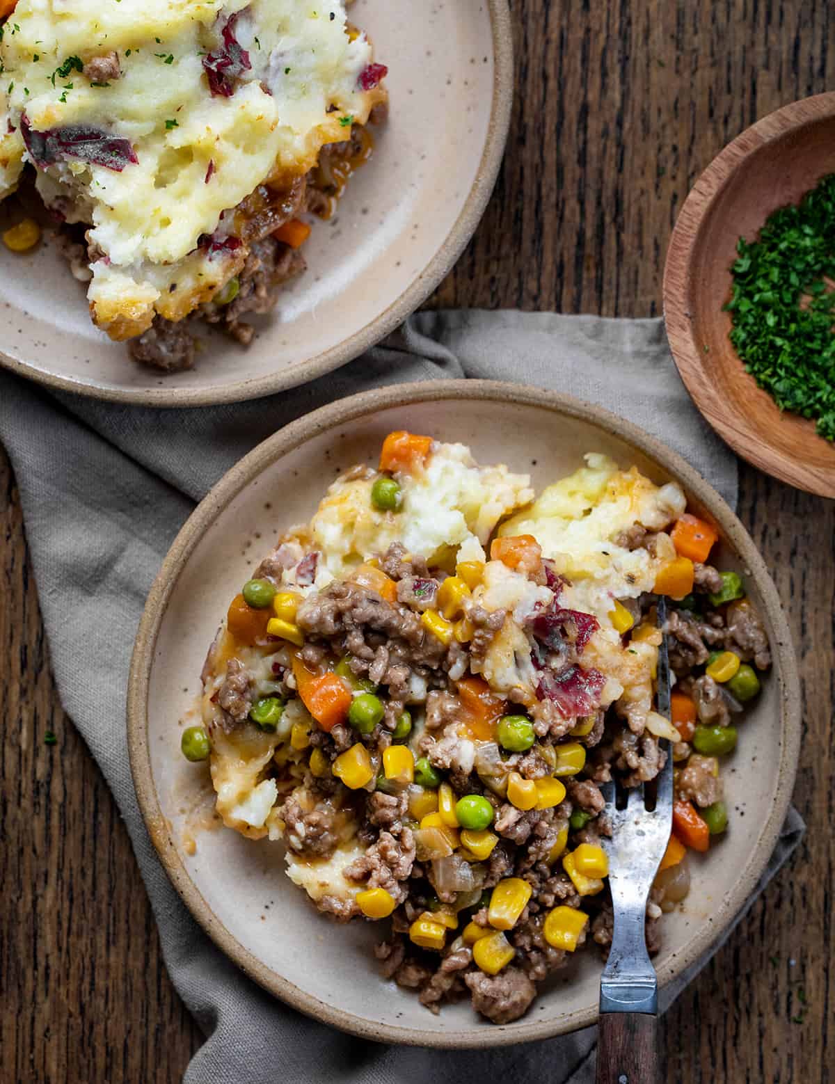 Two plates of Shepherd's Pie on a dark table.