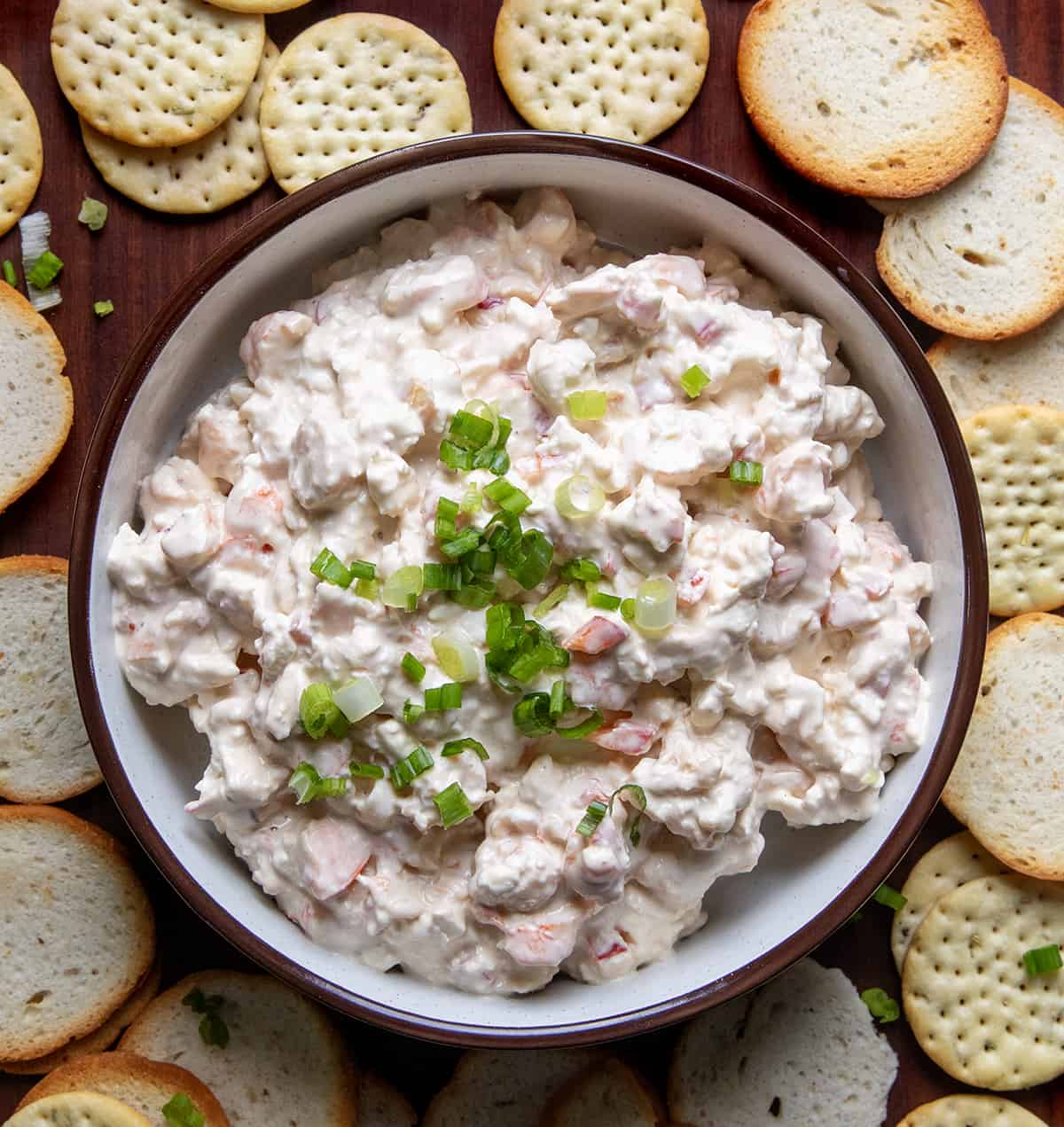 Overhead Image of Shrimp Dip in a Bowl Surrounded by Bagel Chips and Crackers.