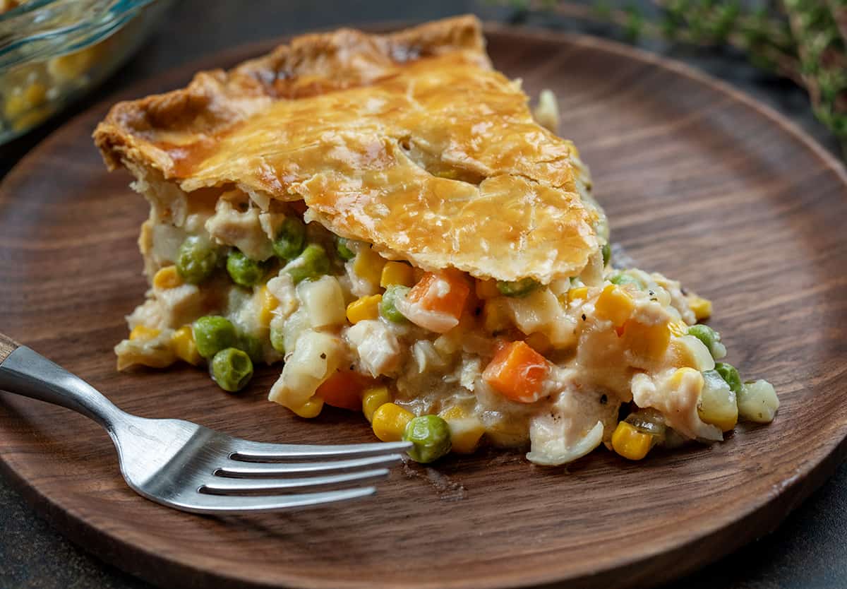 Wooden Plate with a piece of Turkey Pot Pie on it and a fork.