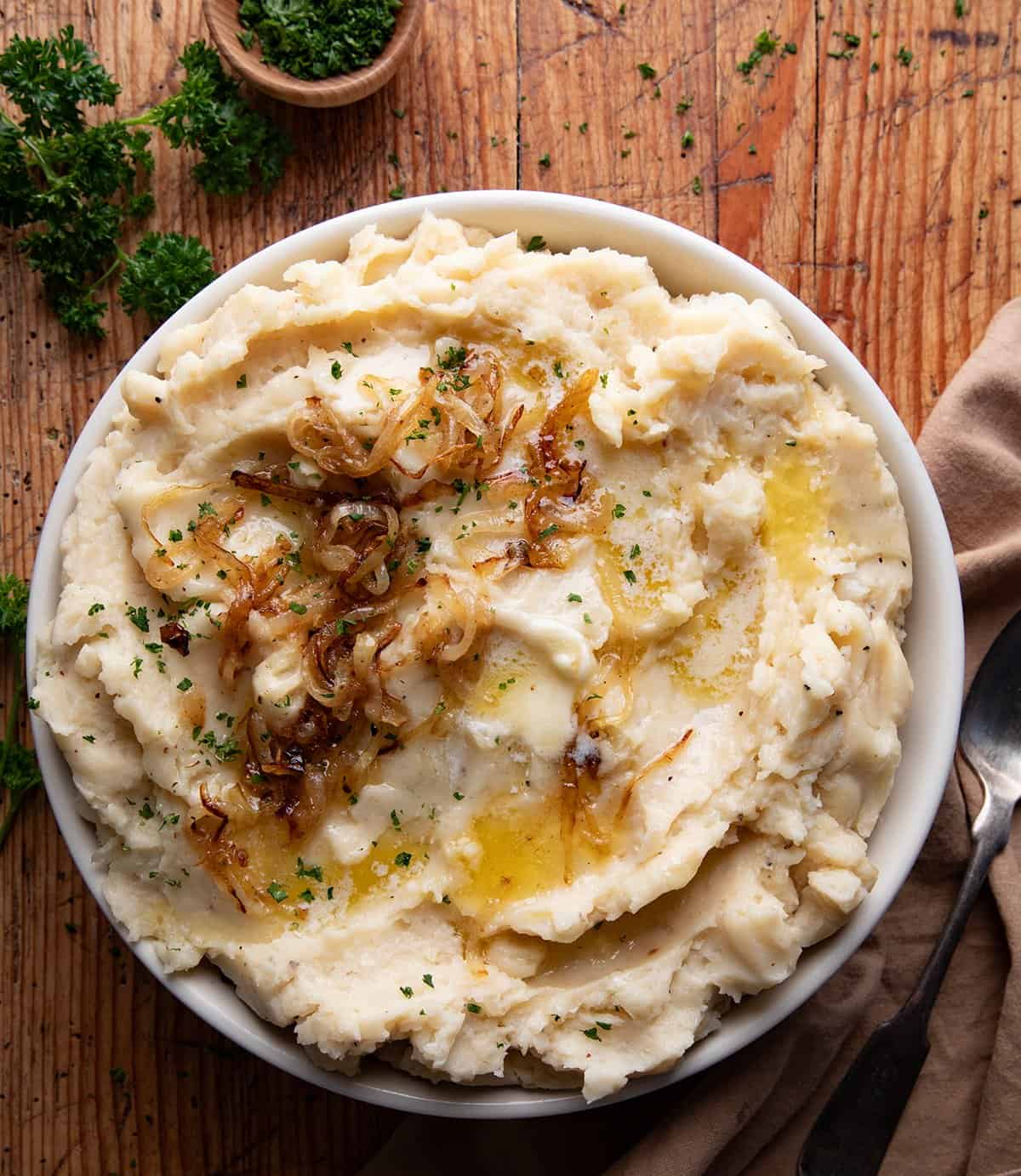 Looking down on a bowl of French Onion Mashed Potatoes on a wooden table. 