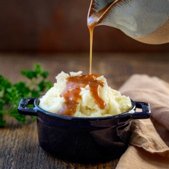 Pouring brown gravy over mashed potatoes.