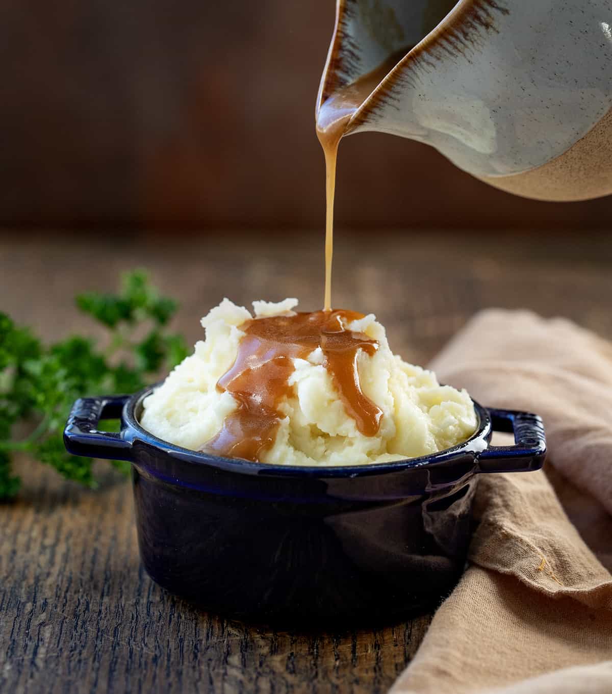 Pouring brown gravy over mashed potatoes.