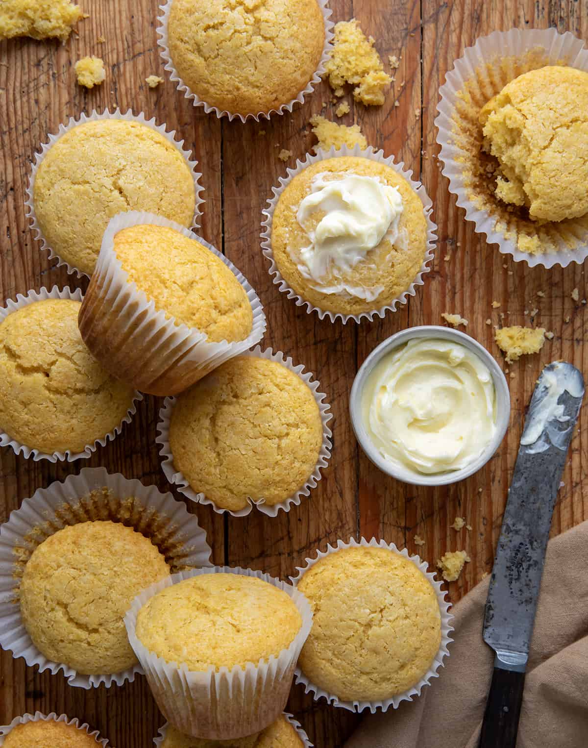 Cornbread Muffins on a table with some butter from overhead.