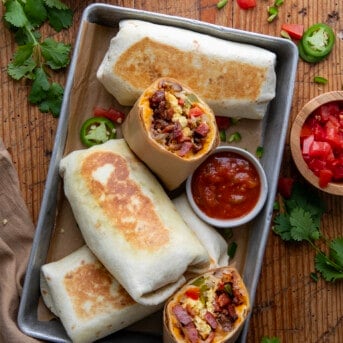 Cowboy Breakfast Burritos in a pan with one cut in half showing inside.
