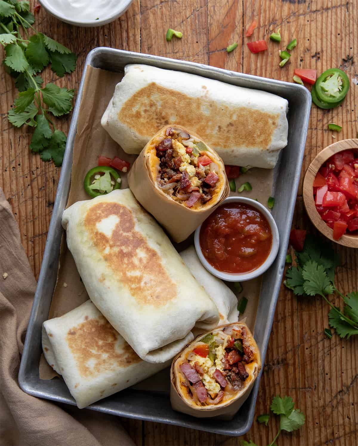 Cowboy Breakfast Burritos in a pan with one cut in half showing inside.