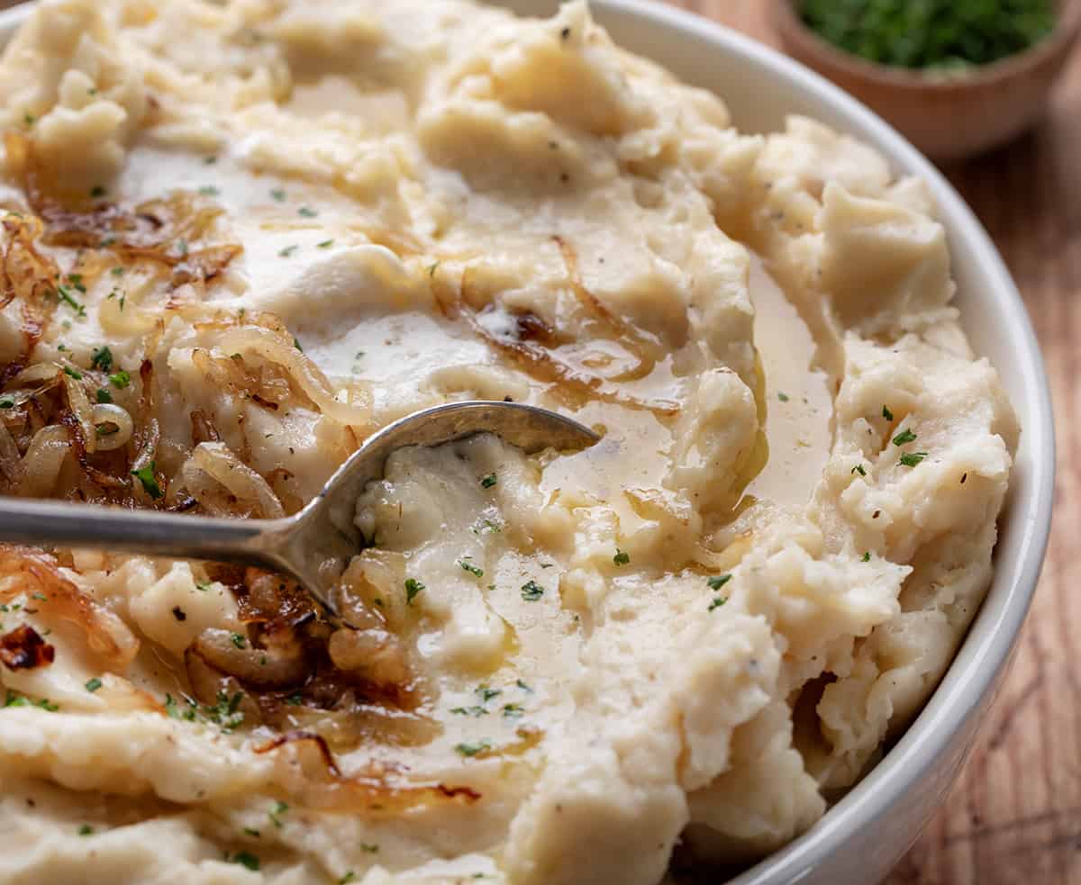 Spoon about to take a portion of French Onion Mashed Potatoes.