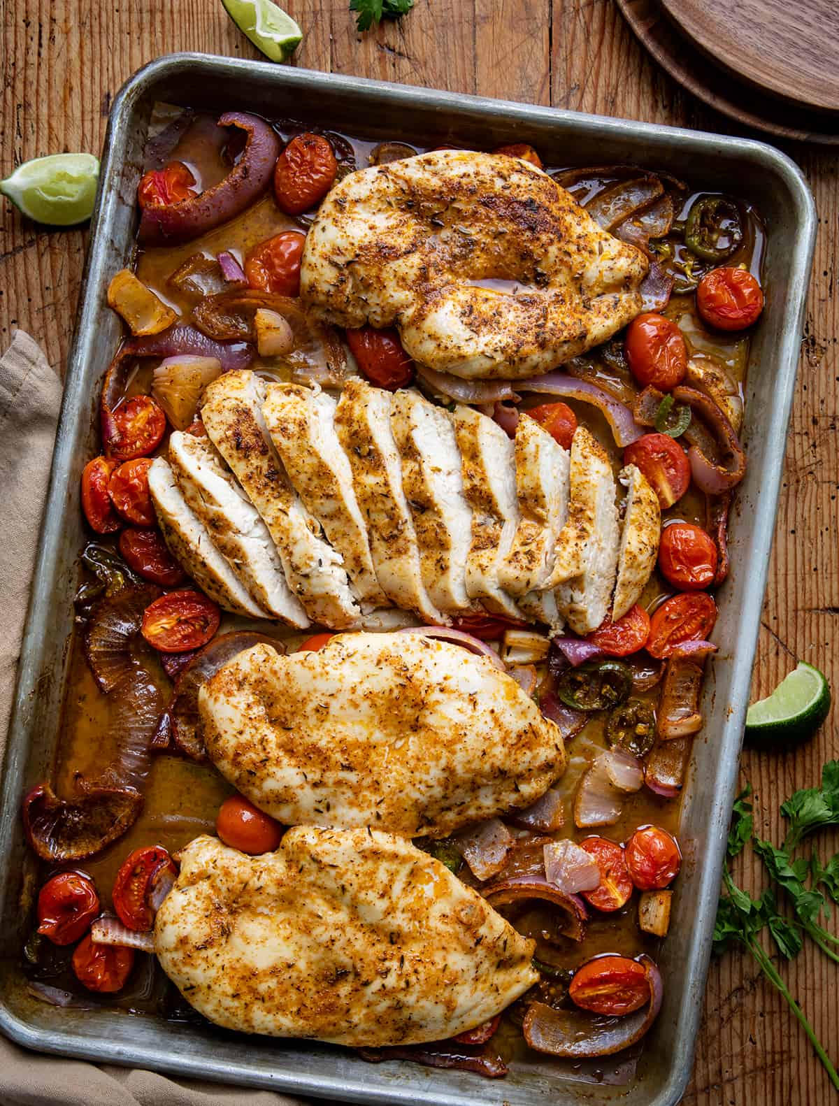 Sheet Pan Roasted Salsa Chicken on a table with one piece of chicken cut into slices.