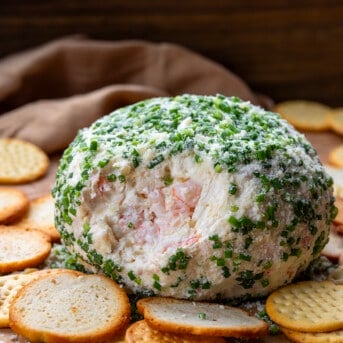 Whole Shrimp Cheese Ball with some of the dip removed showing inside surrounded by crackers.