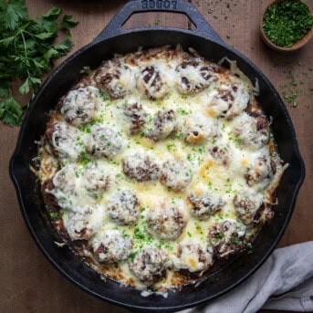 Skillet of French Onion Meatballs on a wooden table from overhead.