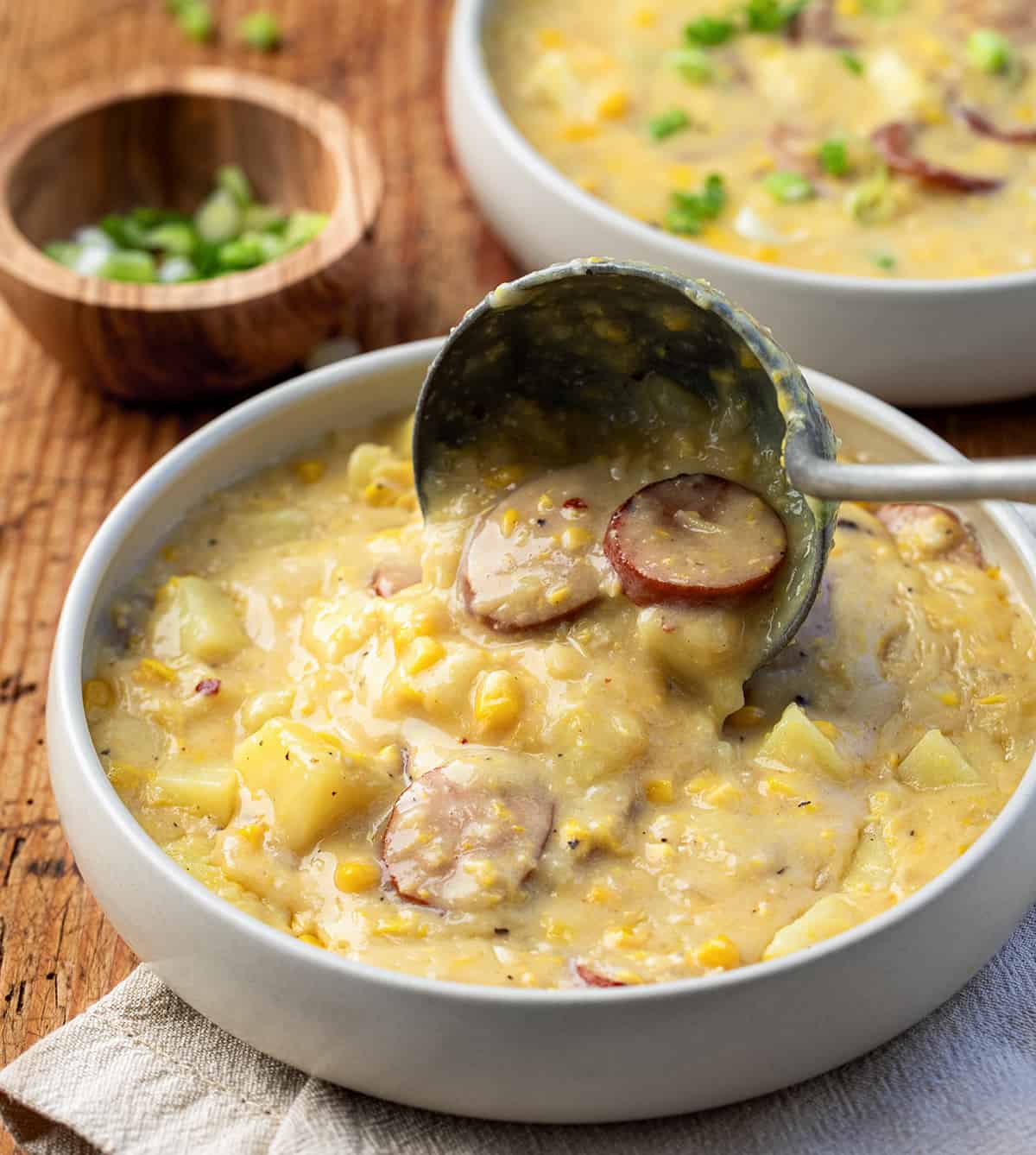 Ladleing Andouille Corn Chowder into a bowl.