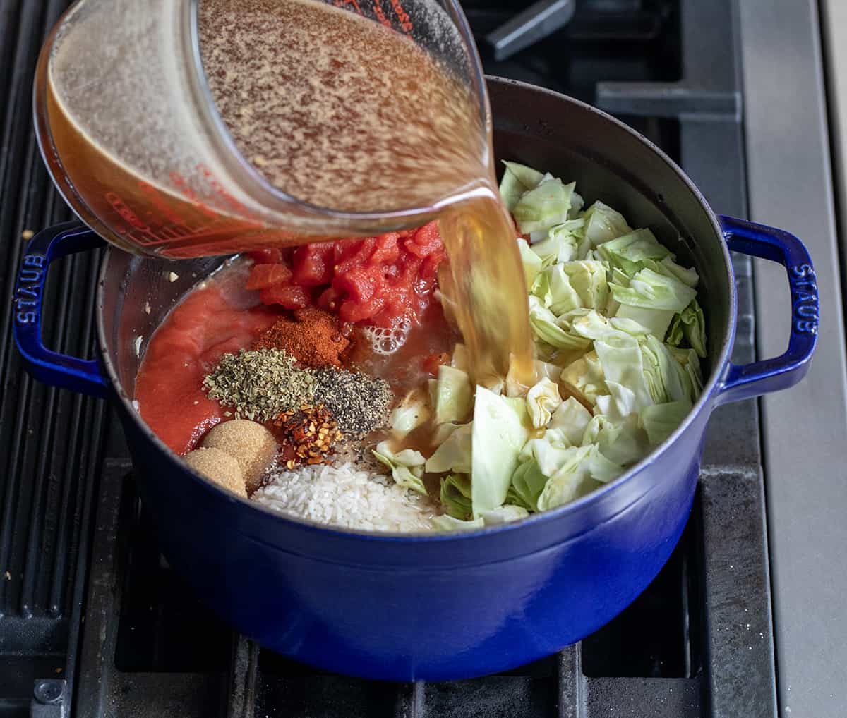 Raw ingredients for Cabbage Roll Soup in a pot over heat.