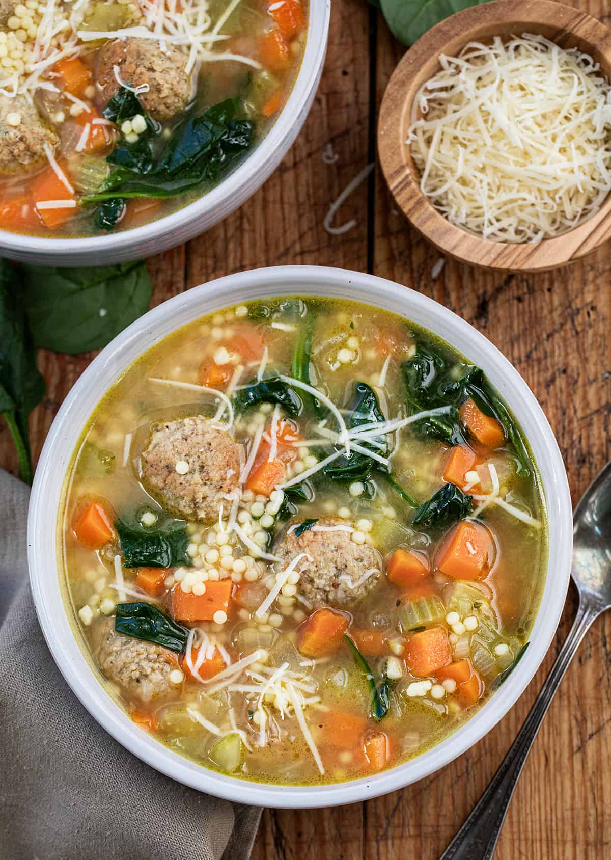 Bowls of Italian Wedding Soup on a wooden table.