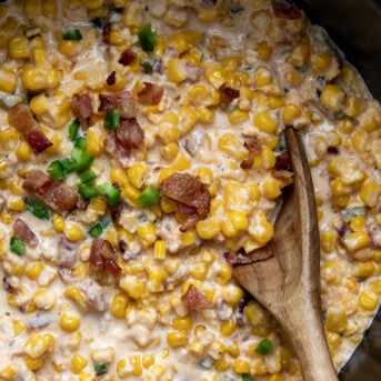 Close up of Slow Cooker Jalapeno Popper Creamed Corn in the slow cooker with a spoon.