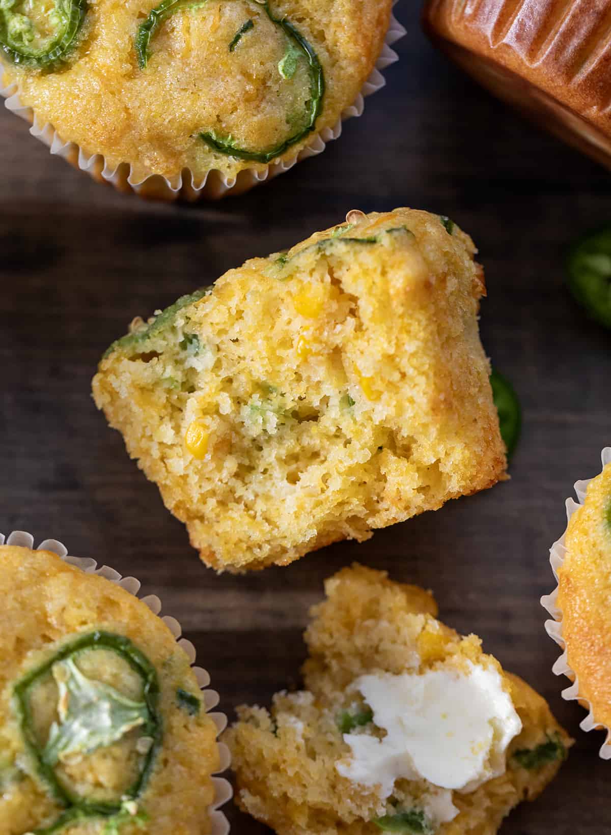 Jalapeno Cheddar Cornbread Muffin on a table cut in half showing inside. 