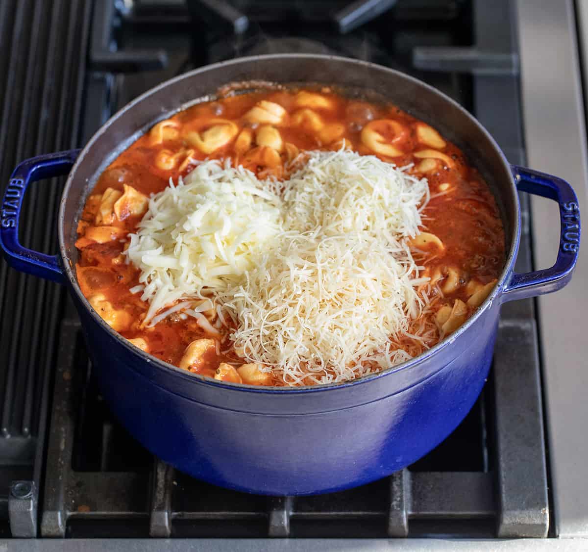 Adding cheeses to Lasagna Soup with Tortellini.