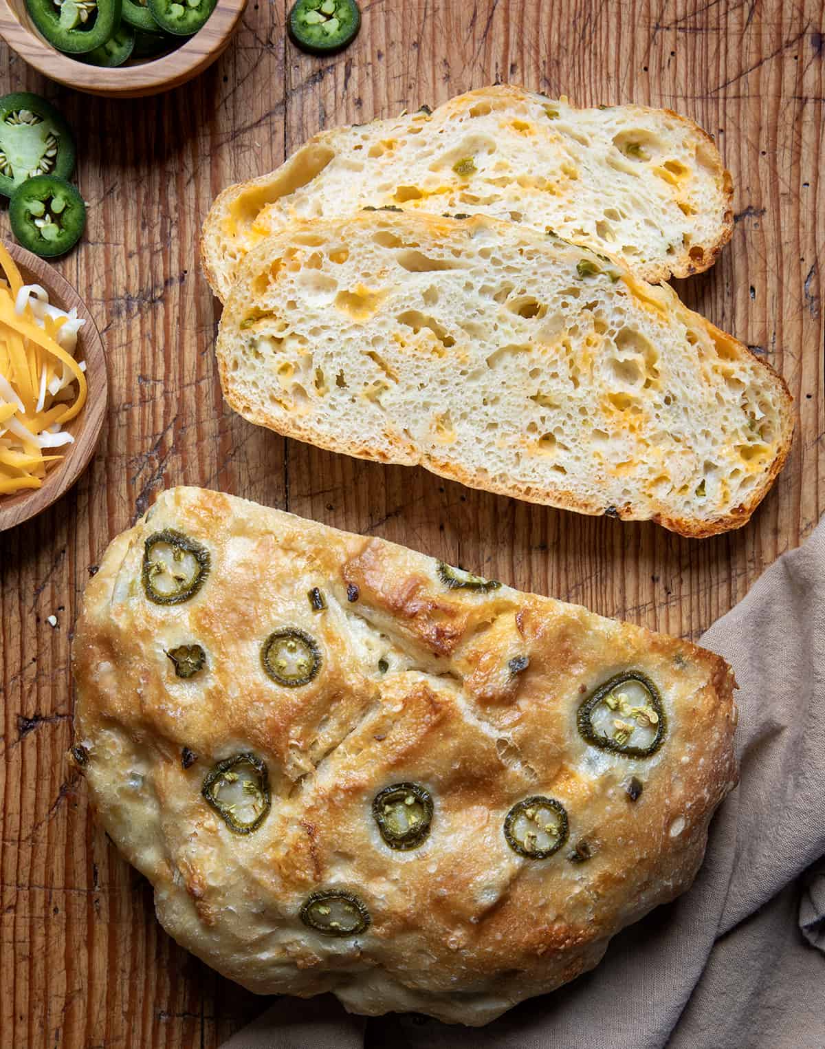 Loaf of Jalapeno Cheddar Bread on a cutting board with a few pieces of the bread cut.