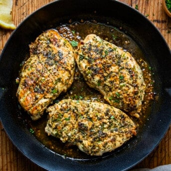 Lemon Garlic Chicken in a skillet on a wooden table from overhead.