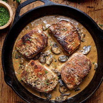 Creamy Mushroom Pork Chops in skillet on a wooden table from overhead.