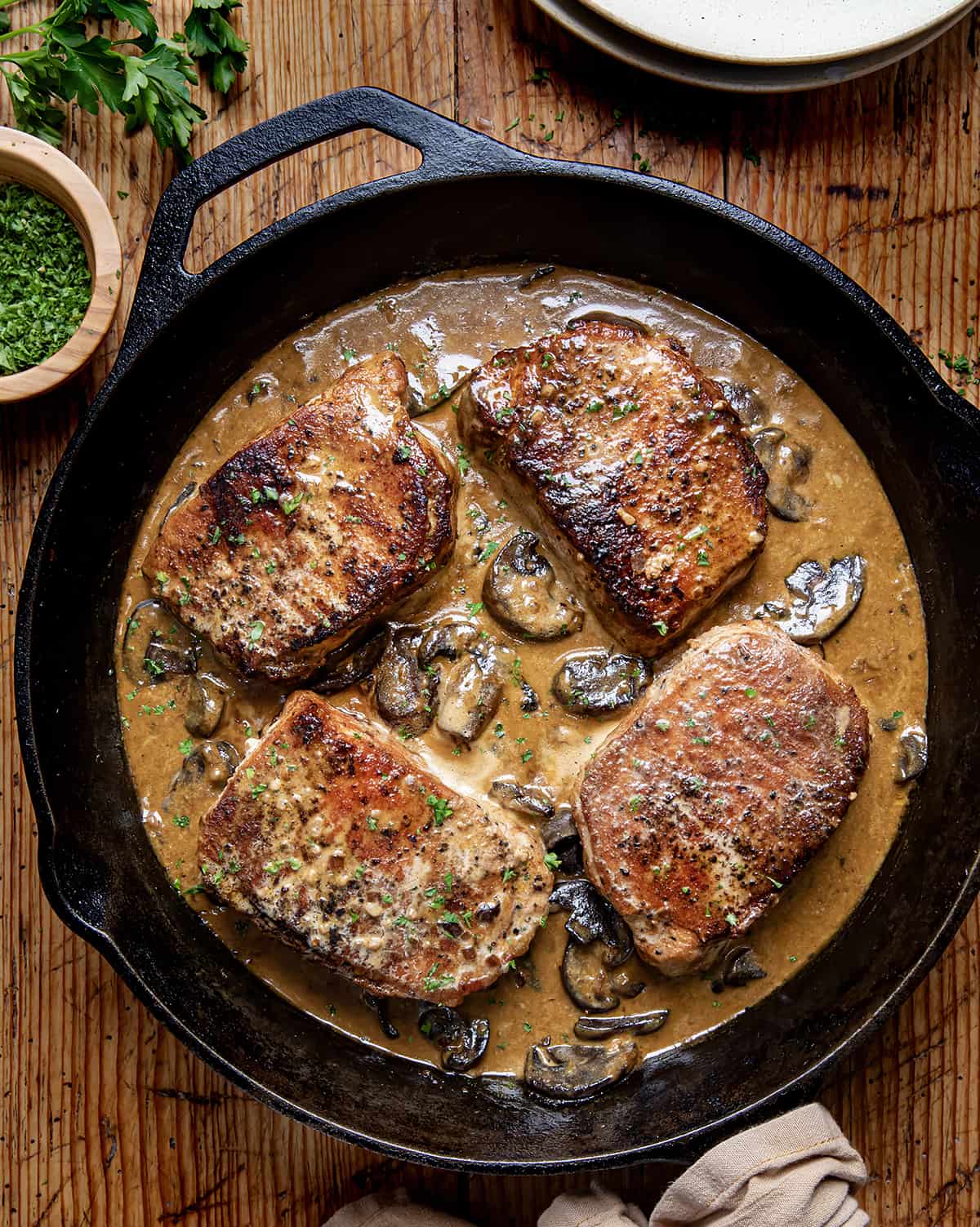 Creamy Mushroom Pork Chops in skillet on a wooden table from overhead.