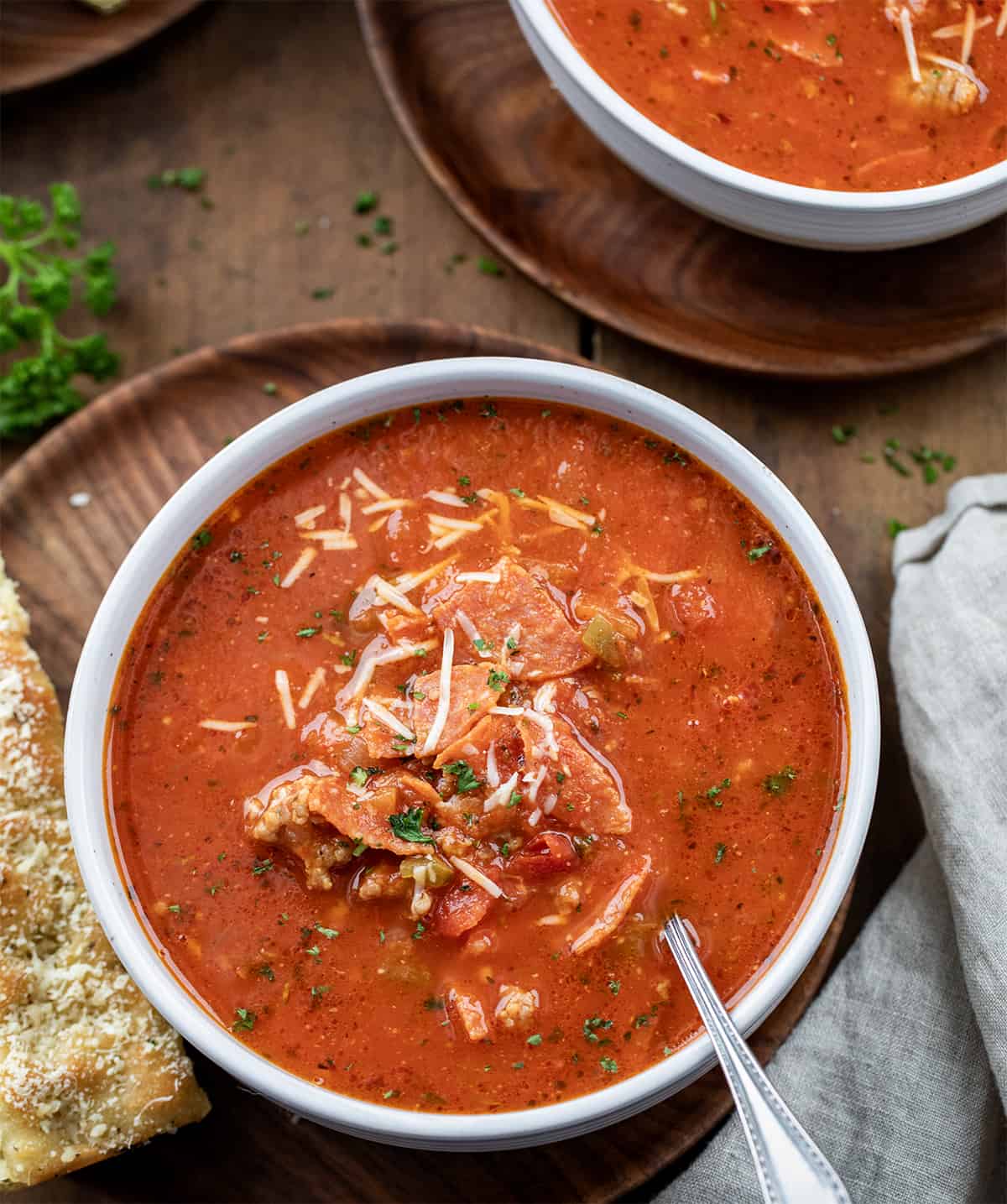 Bowls of Pizza Soup on a wooden table with focaccia.