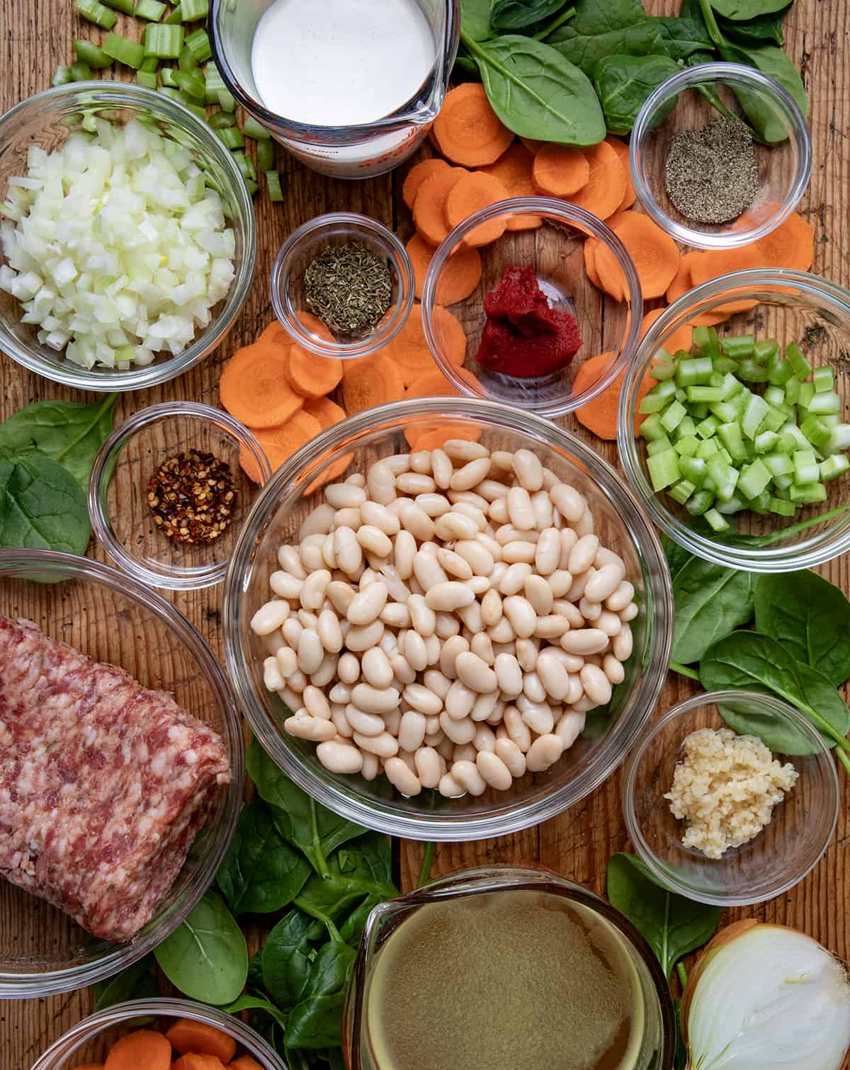 Raw ingredients used for Tuscan White Bean Soup laid out on a table.