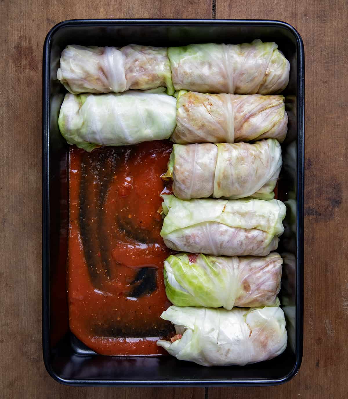 Placing Cabbage Rolls in a pan with sauce.