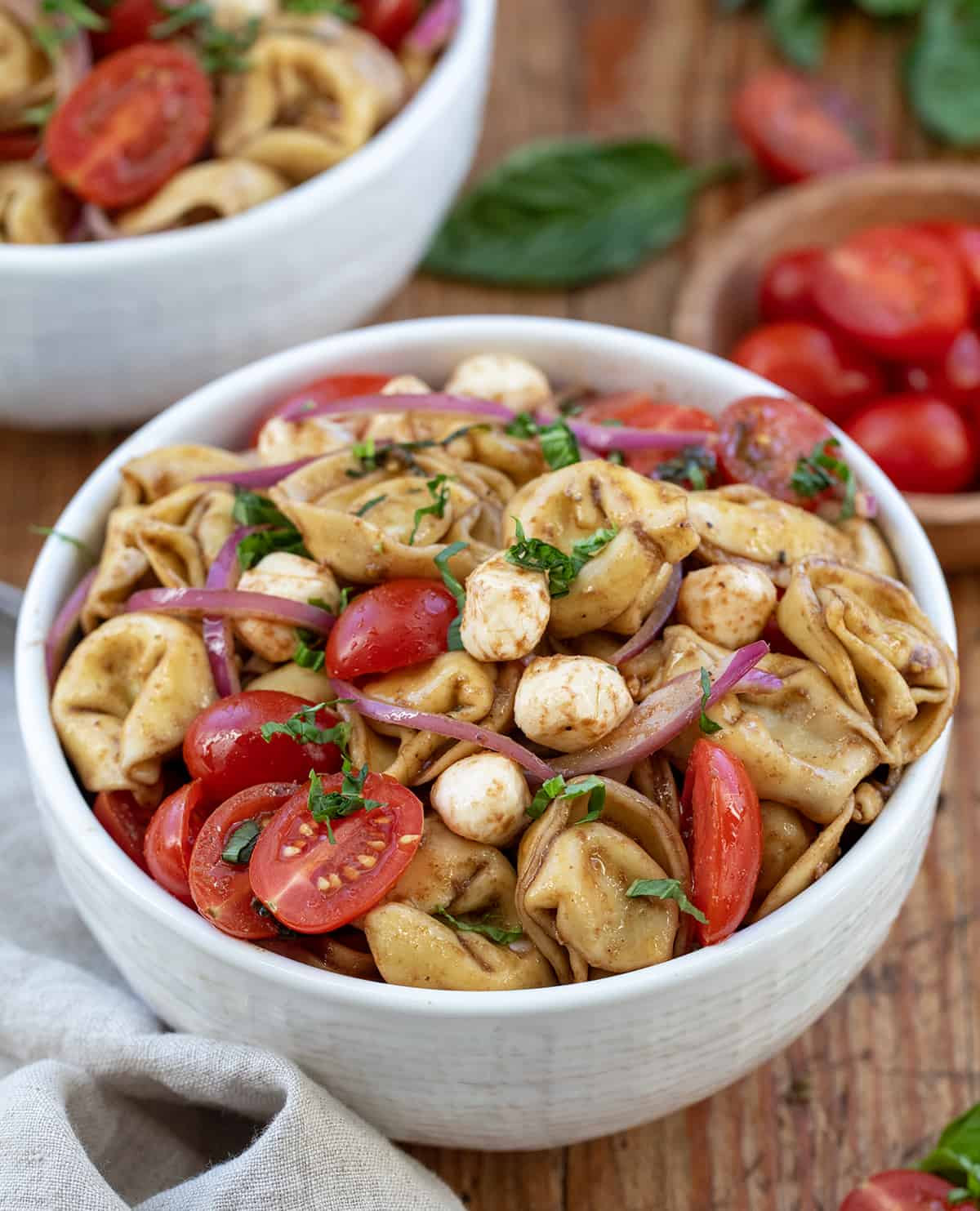 Bowl of Caprese Tortellini Pasta Salad on a wooden table.
