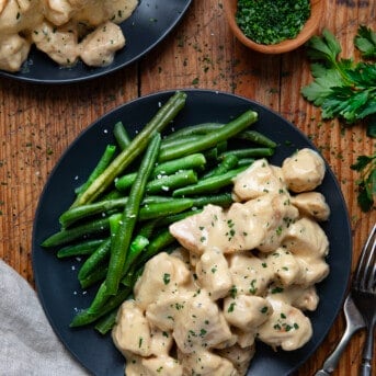 Close up of Caesar Chicken Bites on a plate with a fork and green beans.