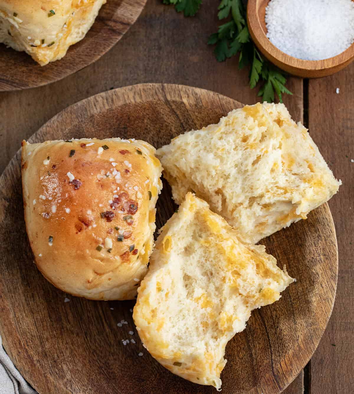 Cheesy Garlic Dinner Rolls on a plate with one roll halved showing the inside texture.