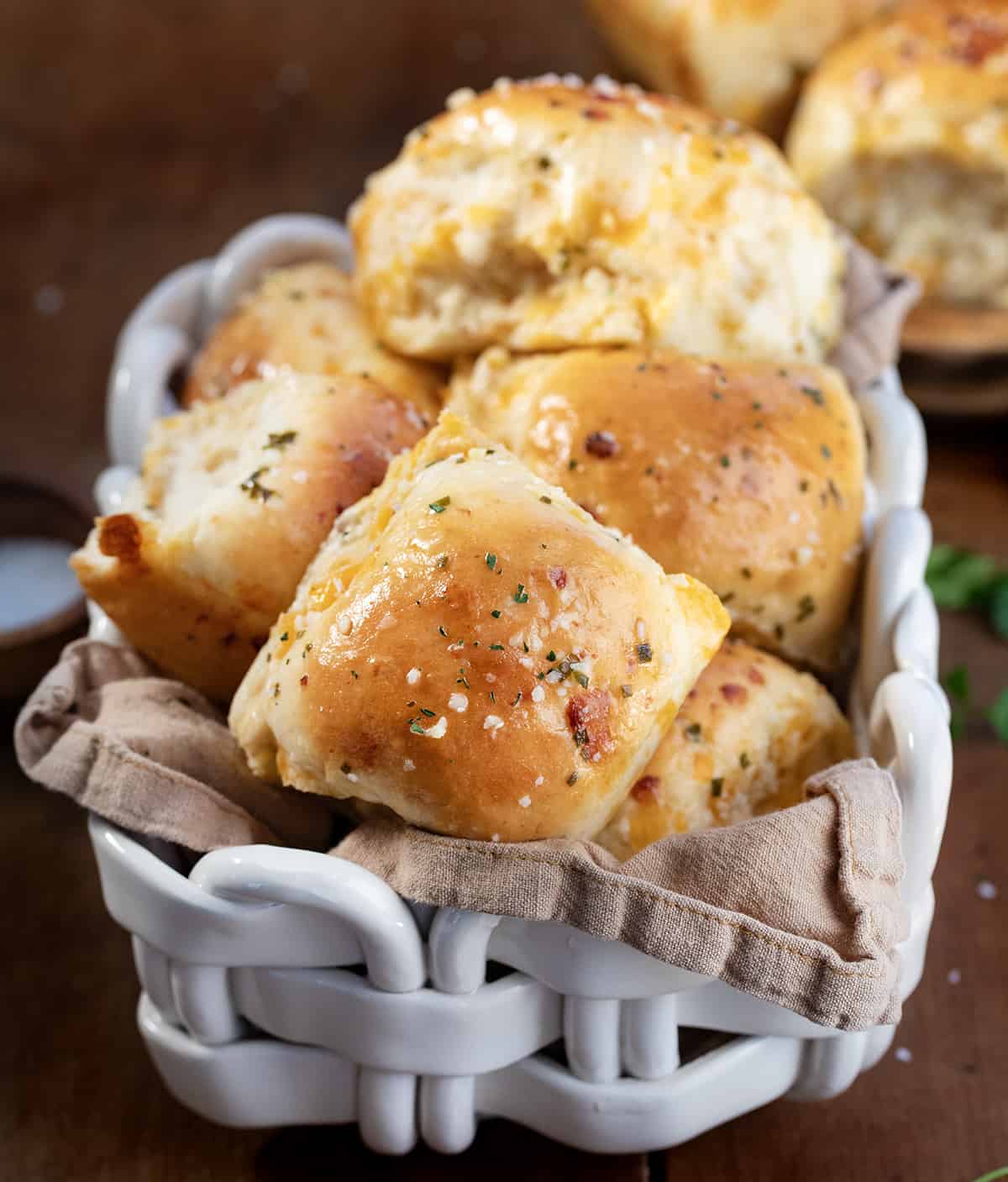 Cheesy Garlic Dinner Rolls in a basket on a wooden table.
