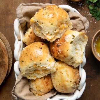Cheesy Garlic Dinner Rolls in a basket on a wooden table from overhead.