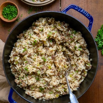 Pot of Easy Dirty Rice on a wooden table with a spoon from overhead.