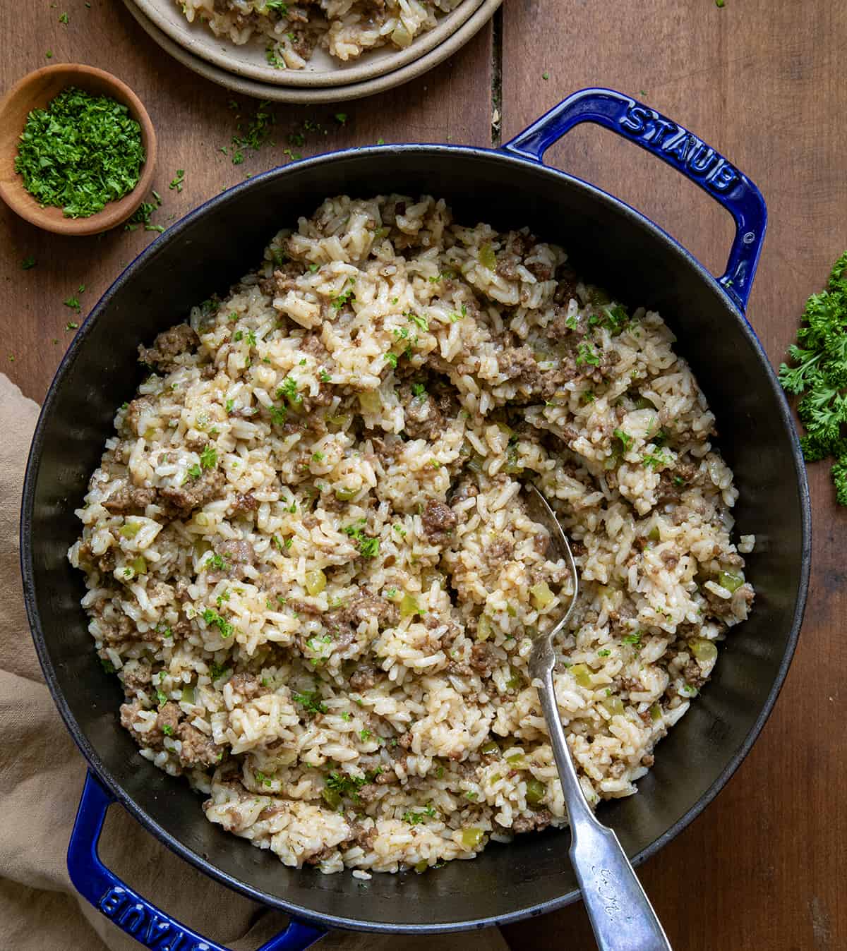 Pot of Easy Dirty Rice on a wooden table with a spoon from overhead. 